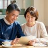 50代の日本人男女がカフェでタブレットや雑誌を見ながら趣味について話し合っている様子。新しい趣味を始める前向きな雰囲気。
