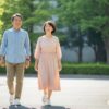 晴れた日、50代の日本人男女が笑顔で並んで歩いている様子。明るい街中での自然な一歩が、前向きな人生のスタートを象徴している。
