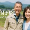 50代の男女が自然豊かな場所で微笑む様子。仕事付き移住による安心感ある新生活のイメージ