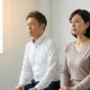 面接会場で緊張した表情を見せる50代の男女。光が差し込む部屋で、不安と希望が入り混じる様子が伝わる。