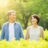 朝の光を浴びながら公園を散歩する、笑顔の50代夫婦。自然の中で穏やかに前向きな時間を過ごす様子