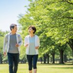 50代の日本人男女が公園を仲良くウォーキングしている様子。健康的なライフスタイルを楽しむ自然な笑顔が印象的なシーン。