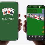 スマートフォンでソリティアゲームをプレイしているシーン。左側の画面はゲーム起動中で、右側は実際にゲームをプレイしている様子が表示されています。カードが並べられたグリーンのテーブルに、操作ボタンやタイマーなどのゲームインターフェースが表示されています。
