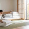 秋の寝具の衣替えをする女性の様子。明るい和室で布団を整える現代的な暮らしのイメージ
