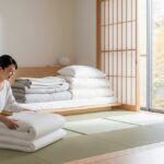 秋の寝具の衣替えをする女性の様子。明るい和室で布団を整える現代的な暮らしのイメージ