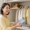 クローゼットで衣替えをする中年女性。湿気やカビ対策を意識した清潔で明るい収納のイメージ